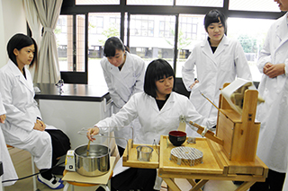 上州座繰り器をあやつり，生糸をつむぐ生徒たち